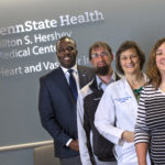 Four people are stand in a row in front of a sign for Penn State Health Milton S. Hershey Medical Center Heart and Vascular Institute.