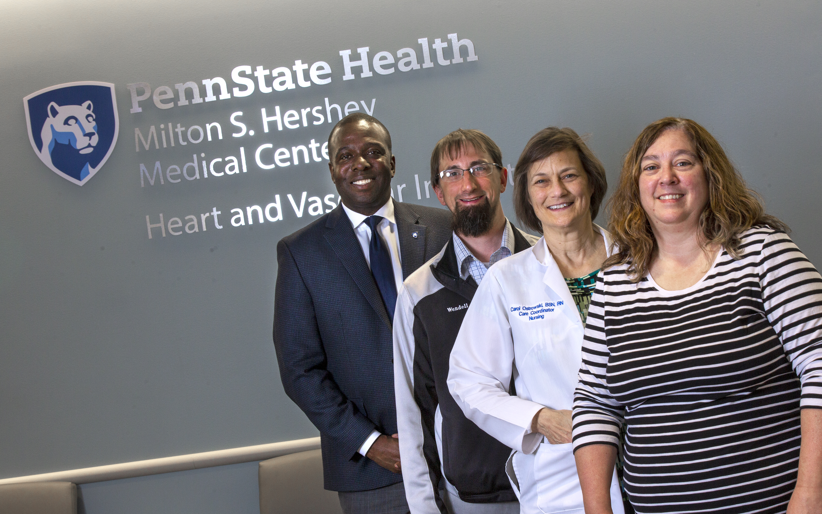 Four people are stand in a row in front of a sign for Penn State Health Milton S. Hershey Medical Center Heart and Vascular Institute.