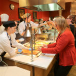 People stand in line in a cafeteria.