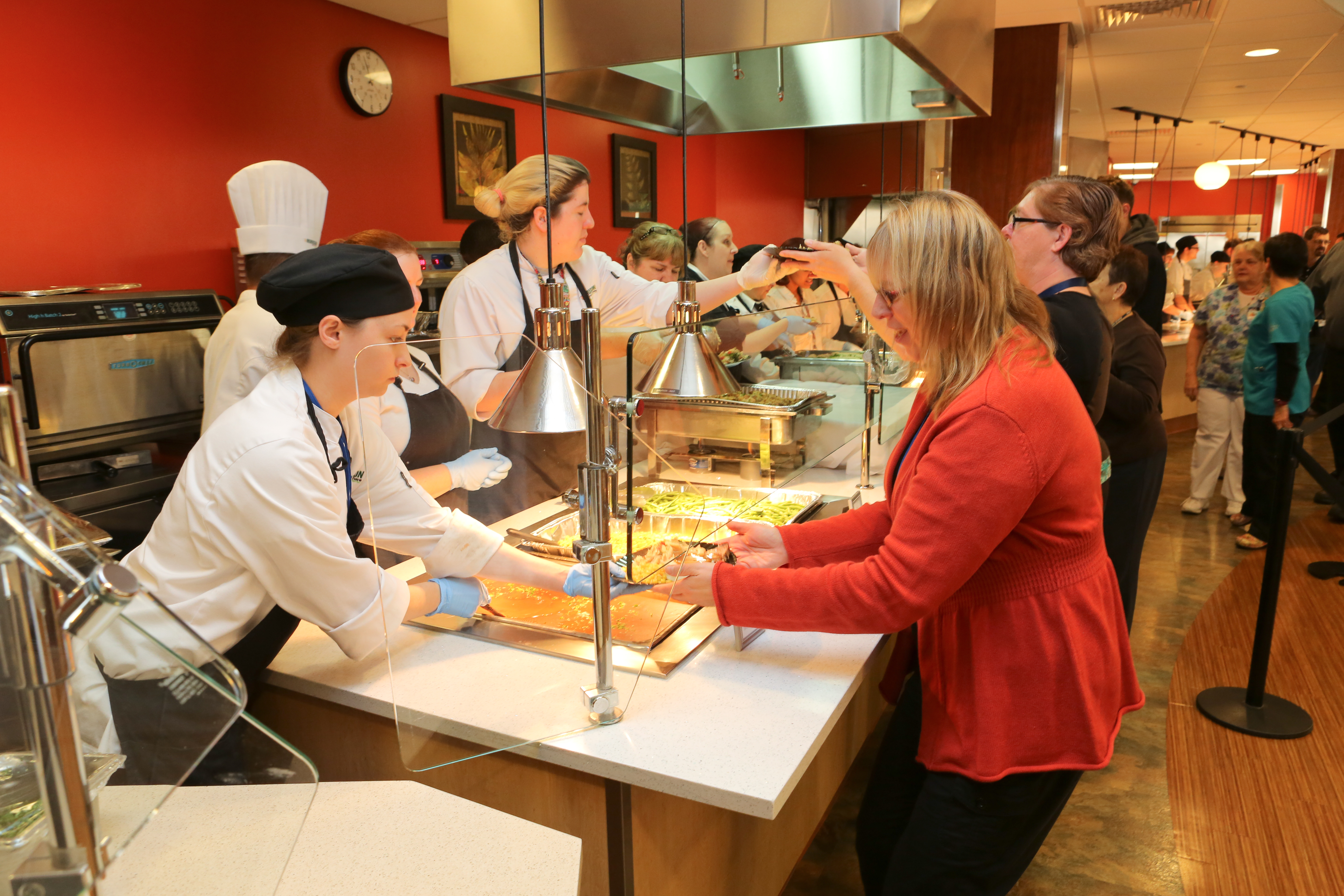 People stand in line in a cafeteria.