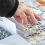 A hand is shown reaching for bandages over vials of serum.