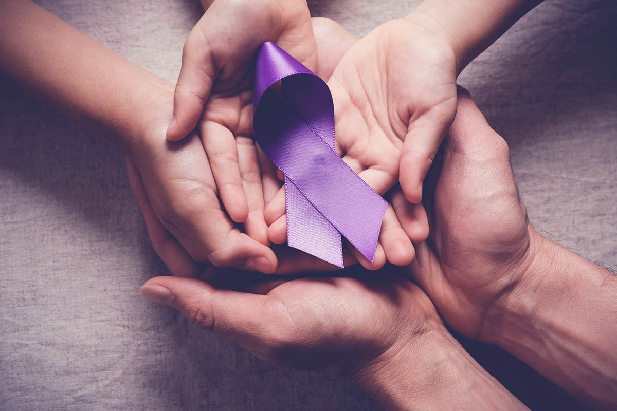 A close-up of three pairs of overlapping hands with a purple, curved ribbon placed on top.