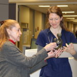 Christine Ewing hands a statue to Elizabeth Etter, who holds a plaque and wears scrubs.