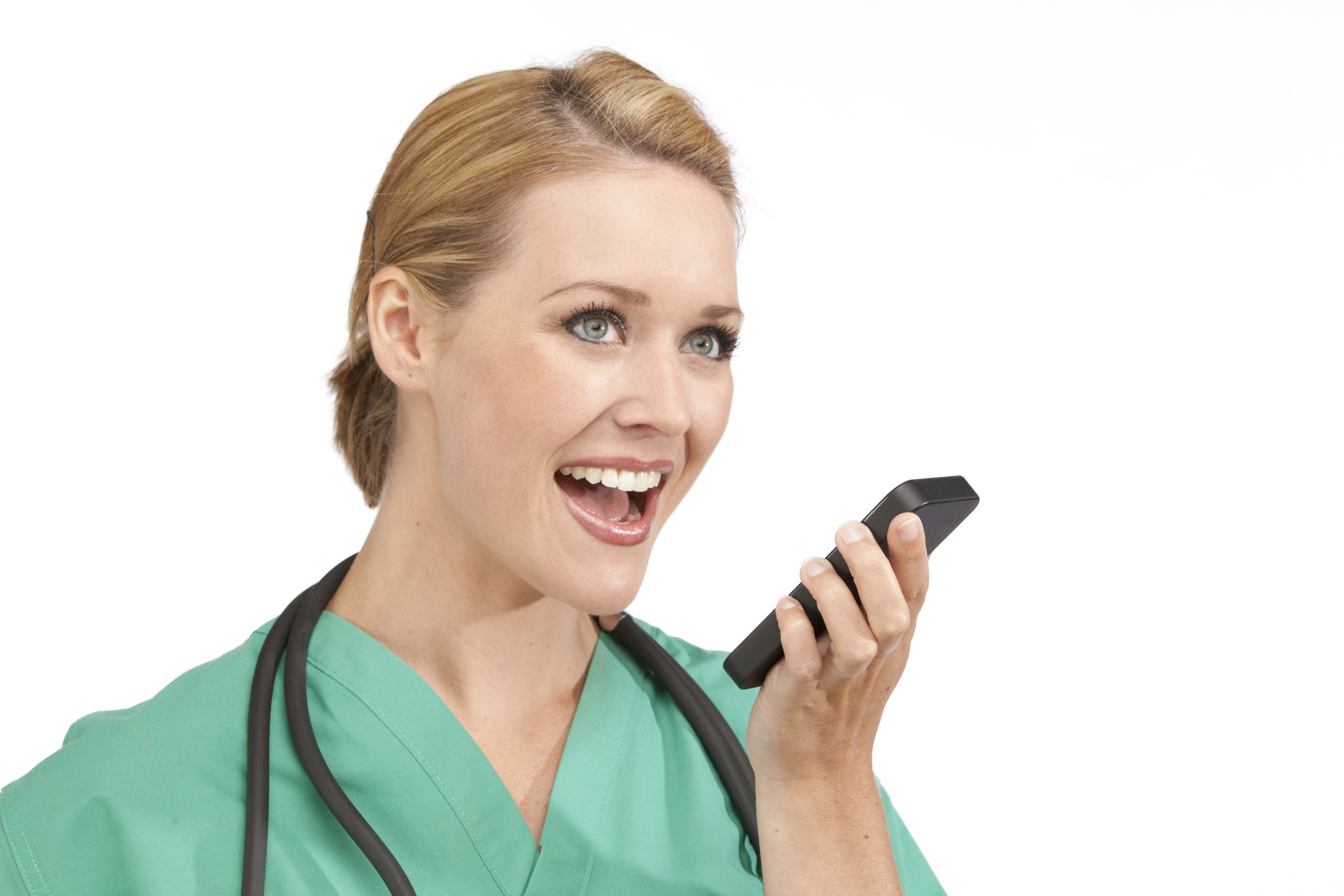 : A woman in medical scrubs talks into a smart phone.