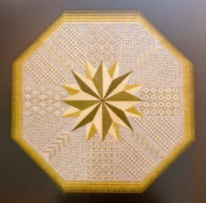 A closeup image of one of Dr. Daniel Hale's needlepoint pieces shows a many-pointed star in the middle of a design.