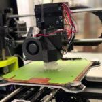 A 3D printer is seen creating a prototype out of moldable material.