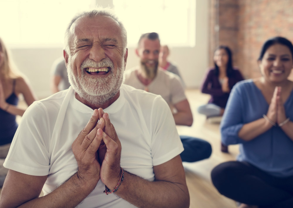 A group of people assume yoga poses and laugh.