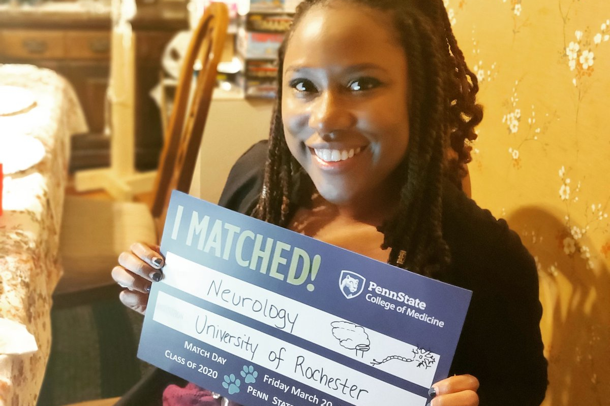 A woman smiles as she holds up a sign that reads: I matched! Neurology; University of Rochester
