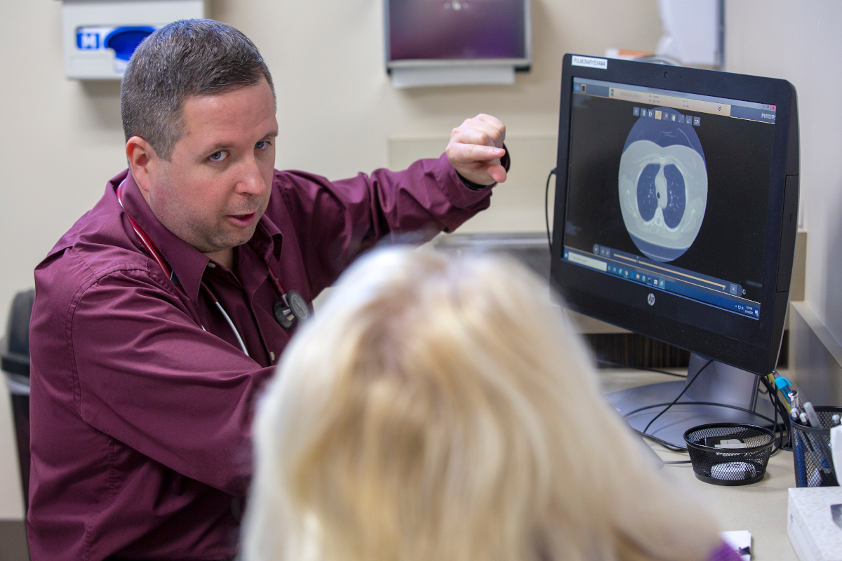 A doctor talks with patient while looking at an image of lungs