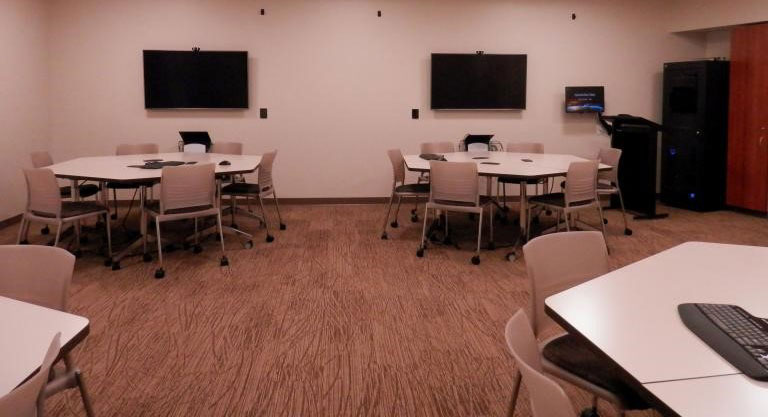Harrell Health Sciences Library's Experimental Classroom includes round tables with chairs, computers, wall-mounted screens and VR headsets.