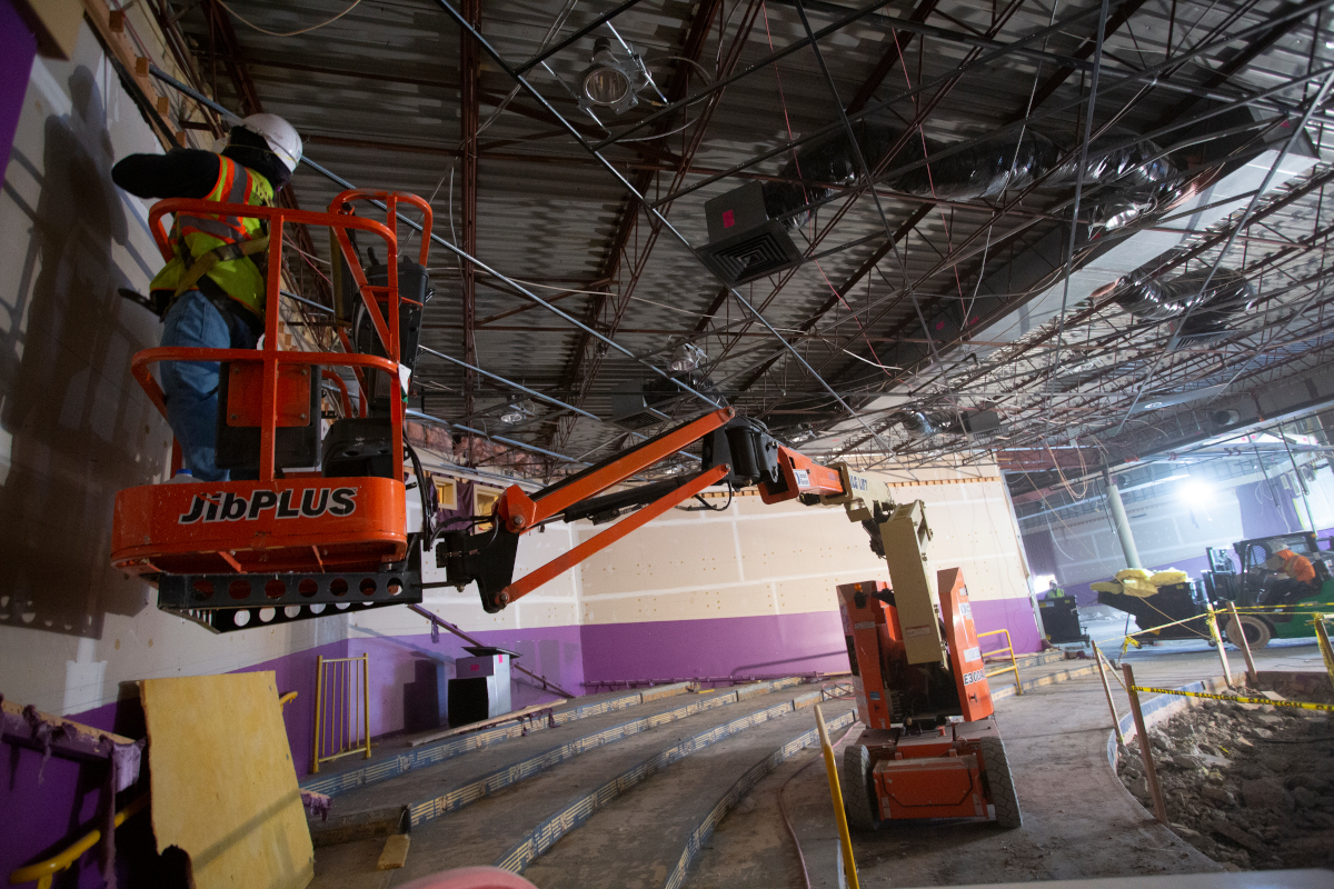 A person stands in a piece of construction equipment working on a building demolition