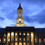 The image shows Penn State’s Old Main against a night sky.