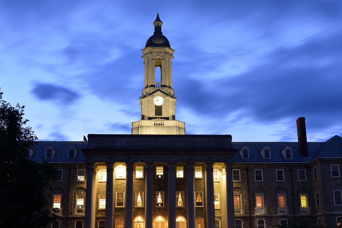 The image shows Penn State’s Old Main against a night sky.