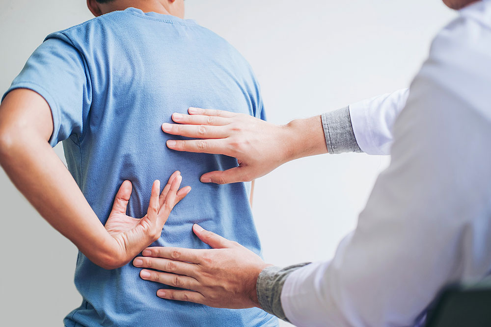 A patient places hand on his back as doctor touches two other spots on the man’s back in this stock image.