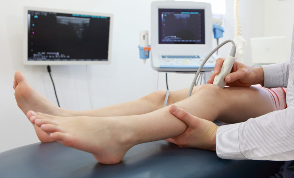 A knee ultrasound is being performed in this stock image.