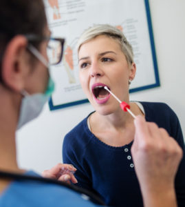 A saliva test is conducted by swabbing the inside of the mouth of a woman with her mouth open in this stock photo.