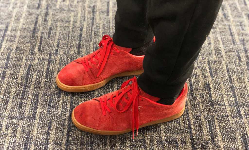 A closeup photo shows a pair of red sneakers on someone's feet.