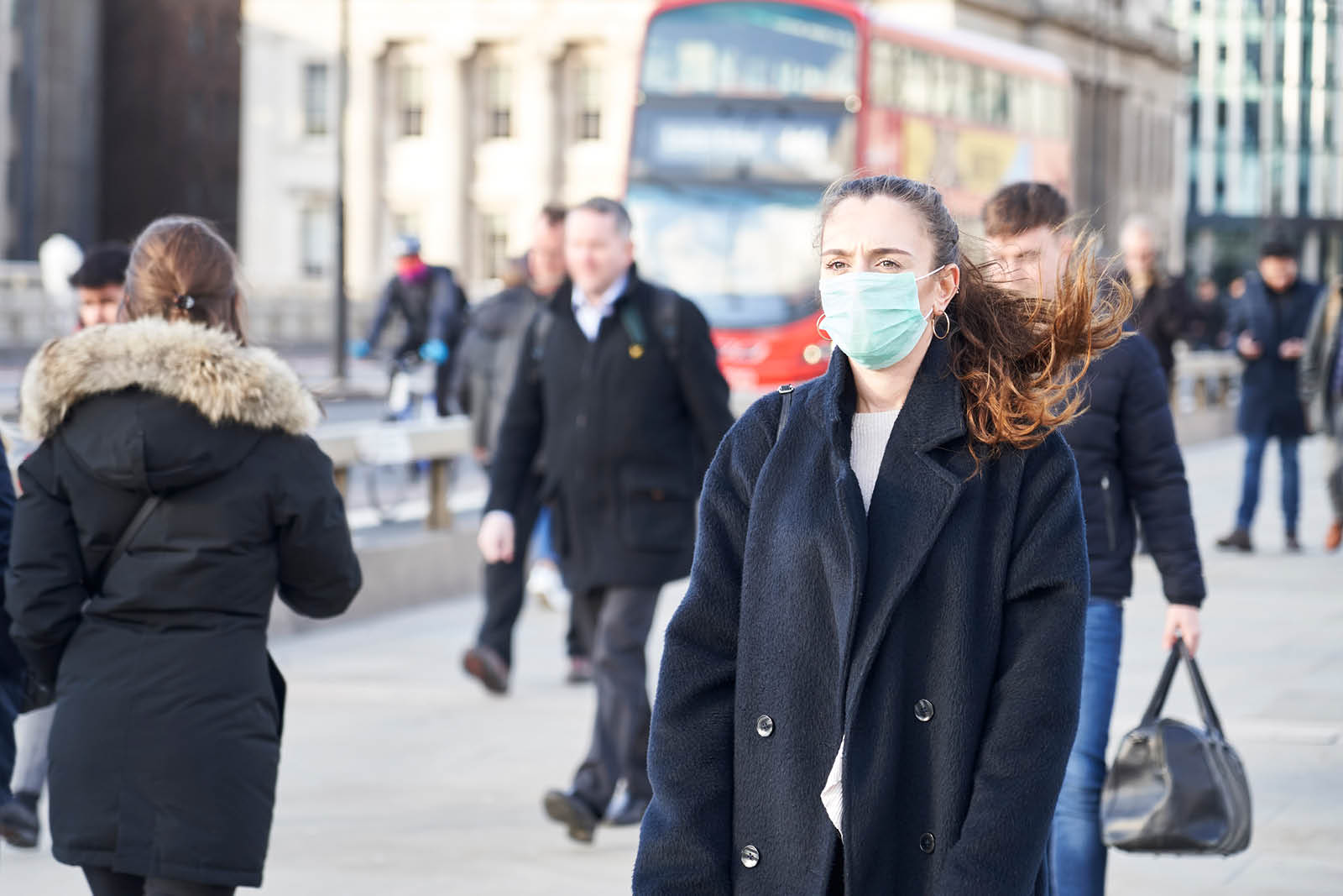 People walk down a city street, some wearing face masks, others not.