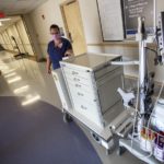 Tina Hedgepeth, a registered nurse at Hershey Medical Center, stands next to the motorized cart. One part is a huge cabinet on wheels with five drawers. It hitches to the other part, which includes baskets for storing items and a monitor mounted on a pole.