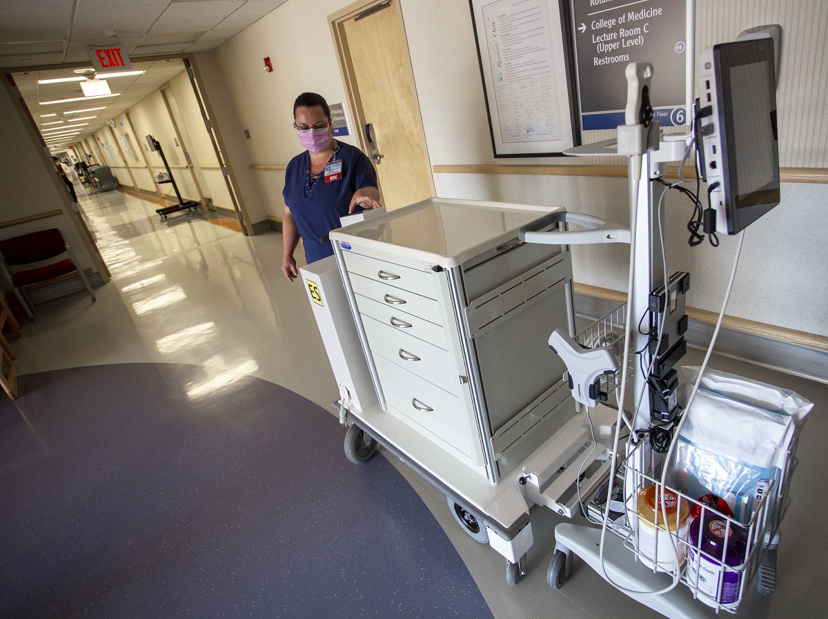 Tina Hedgepeth, a registered nurse at Hershey Medical Center, stands next to the motorized cart. One part is a huge cabinet on wheels with five drawers. It hitches to the other part, which includes baskets for storing items and a monitor mounted on a pole.