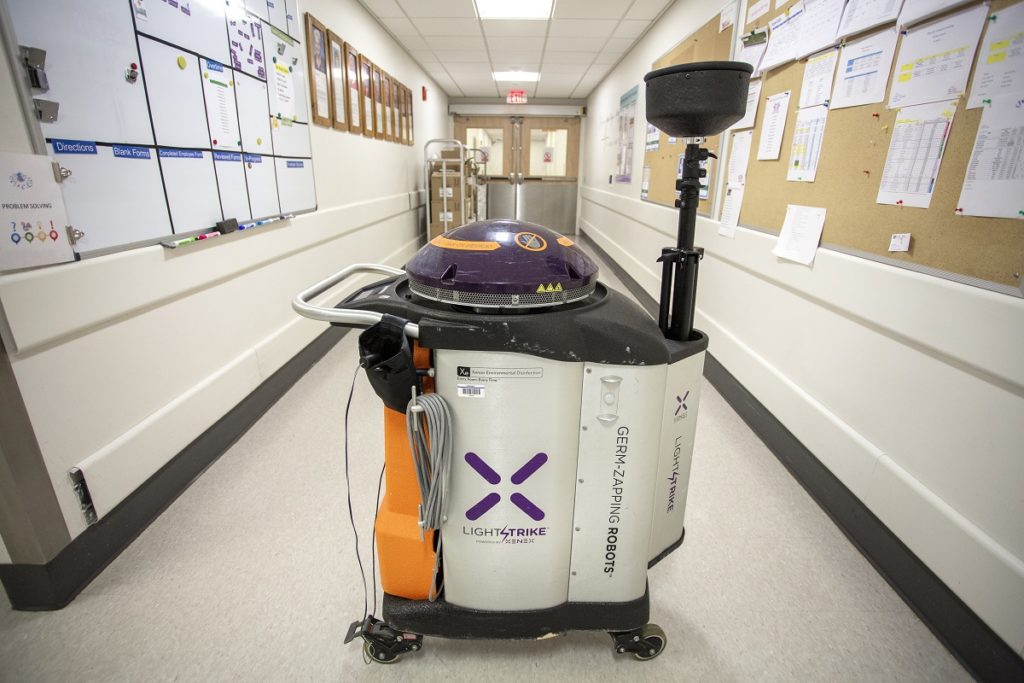 A Xenex robot cleans a hallway at Hershey Medical Center. It looks like a humungous trash can with a lid can on wheels.