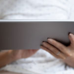 A stock image shows a woman's hands holding a digital tablet device.
