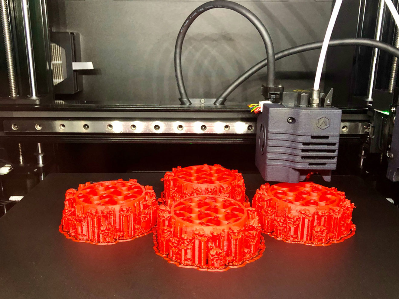 Four large models of COVID-19 viruses that have been made with a 3D printer are seen with the printer in the background.