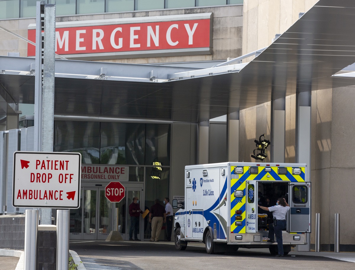 An ambulance pulls up to the new emergency entrance at Hershey Medical Center. A sign points ambulances to go right and patient drop offs to go left.