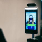 Video camera takes close-up thermal scan of woman. Woman is seen from behind out of focus and in shadow.