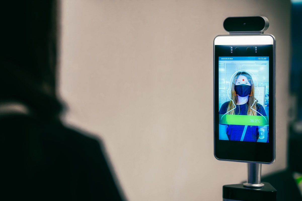 Video camera takes close-up thermal scan of woman. Woman is seen from behind out of focus and in shadow.