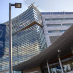 A view from the ground near the main entrance of Hershey Medical Center. A Penn State Health banner is in the foreground; the building is behind it.