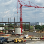 A hospital construction site shows a crane and steel beams