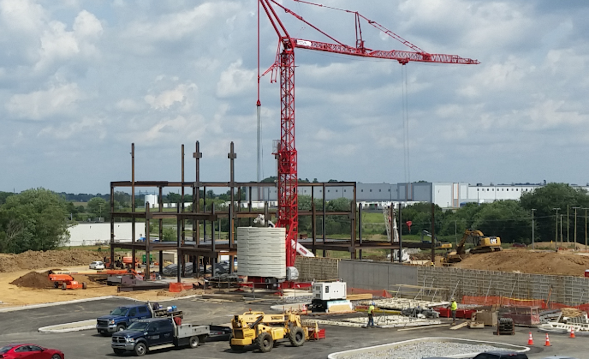 A hospital construction site shows a crane and steel beams