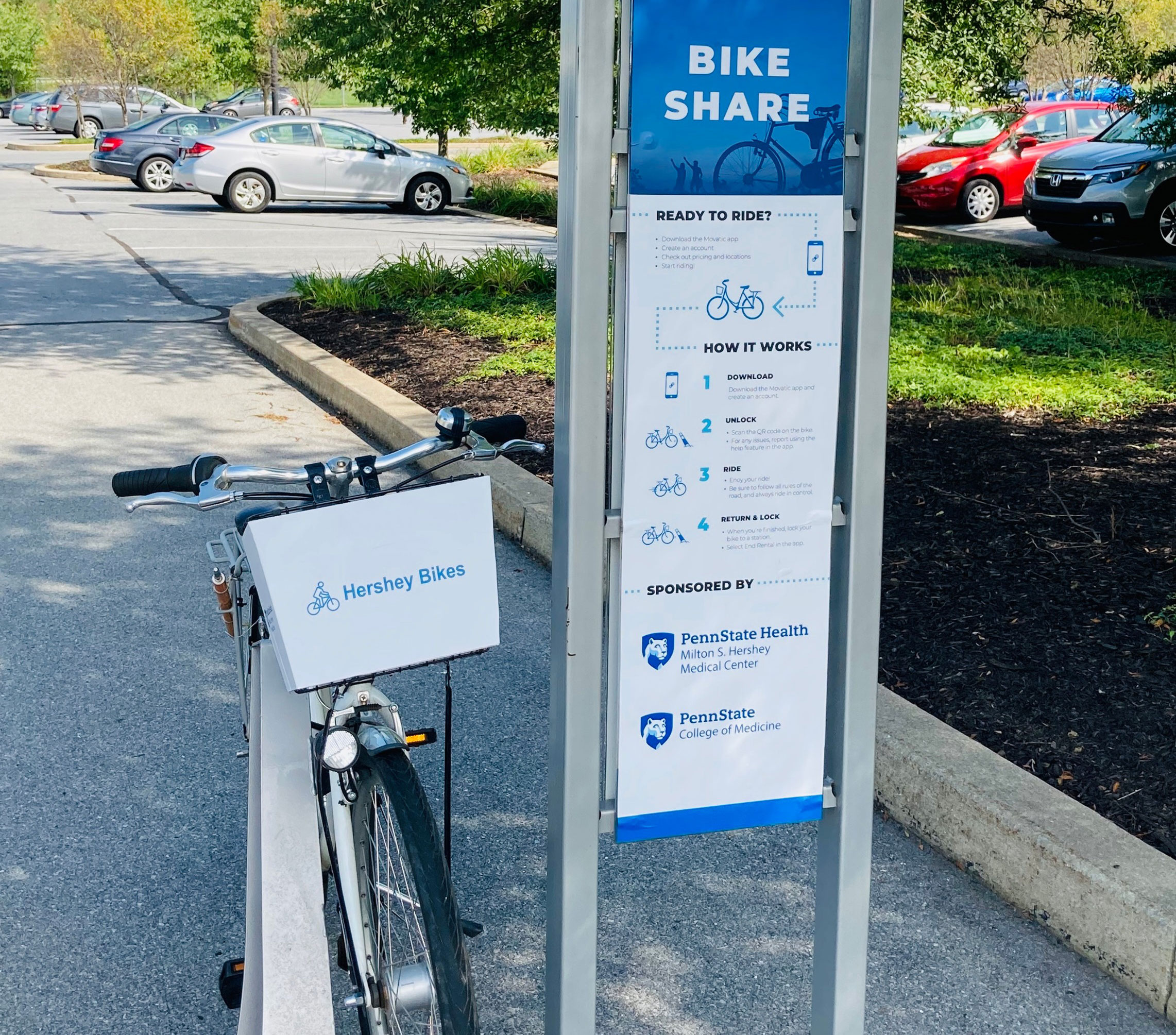 A bicycle is seen on a rack next to a sign describing the bike share program.