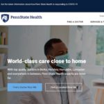 A screenshot of the new Penn State Health website home page, showing a seated physician in a lab coat and wearing a mask talking with an elderly woman, also seated and wearing a mask. Written navigation for the website is at the top and in the middle of the page.