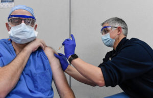 Un hombre le da a un médico una vacuna en el brazo