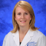 Head and shoulders photo of Dr. Sarah Iriana. She has shoulder length strawberry blonde hair and is wearing a white coat.