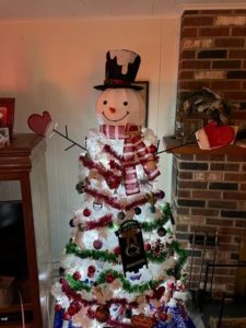 A Christmas tree is shaped like a snowman with arms spread wide.