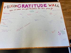 A large piece of post board reads “PSUCOM GRATITUDE WALL. Who or what are you thankful for this year?” Below, the board is covered in handwritten comments.