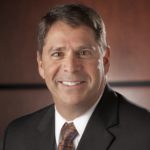 I head and shoulders photo of Don McKenna, who has short, dark hair and a black suit jacket.