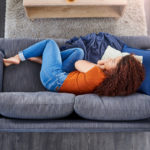 Shot of a young woman lying on the sofa at home and looking depressed