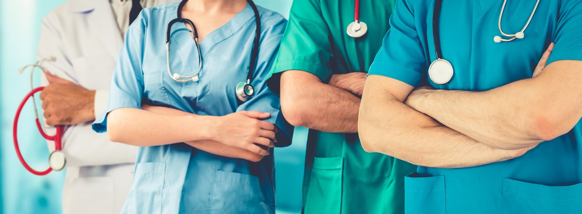 Health care workers stand with arms crossed holding stethoscopes.