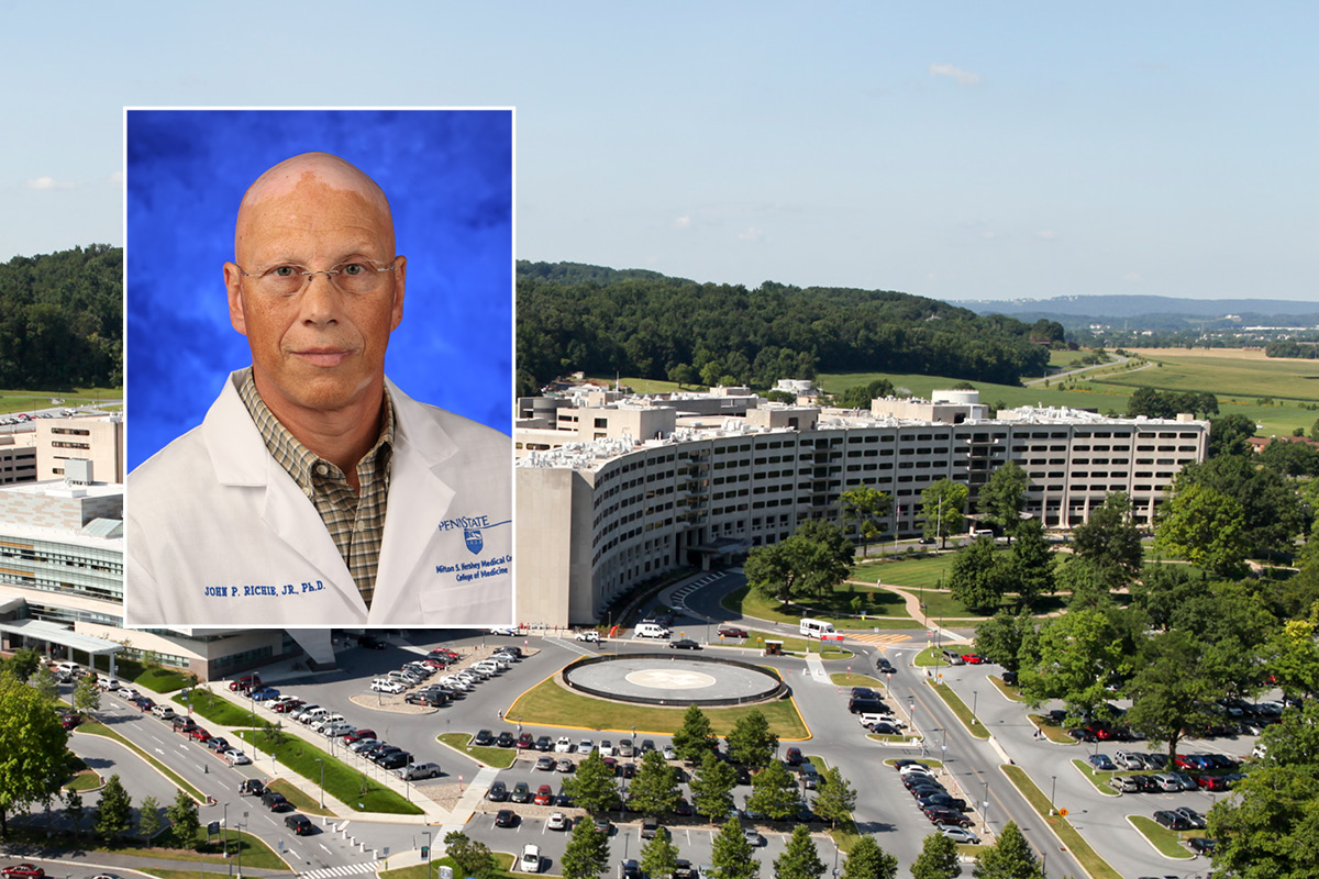 A head and shoulders professional portrait of John Richie against a background photo of Penn State College of Medicine