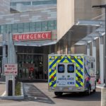 A Life Lion EMS ambulance sits in front of the Hershey Medical Center Emergency Department. A golf cart is on the sidewalk. A sign with the words: Emergency, Trauma Center, is on the right.