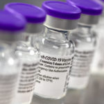 A close-up of several small bottles of COVID-19 vaccine, side by side.