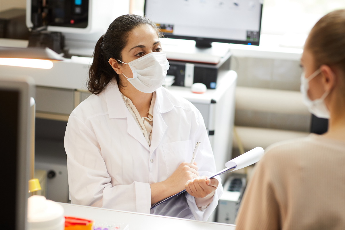 A doctor wearing a paper mask has a conversation with a clinical trial participant wearing a paper mask
