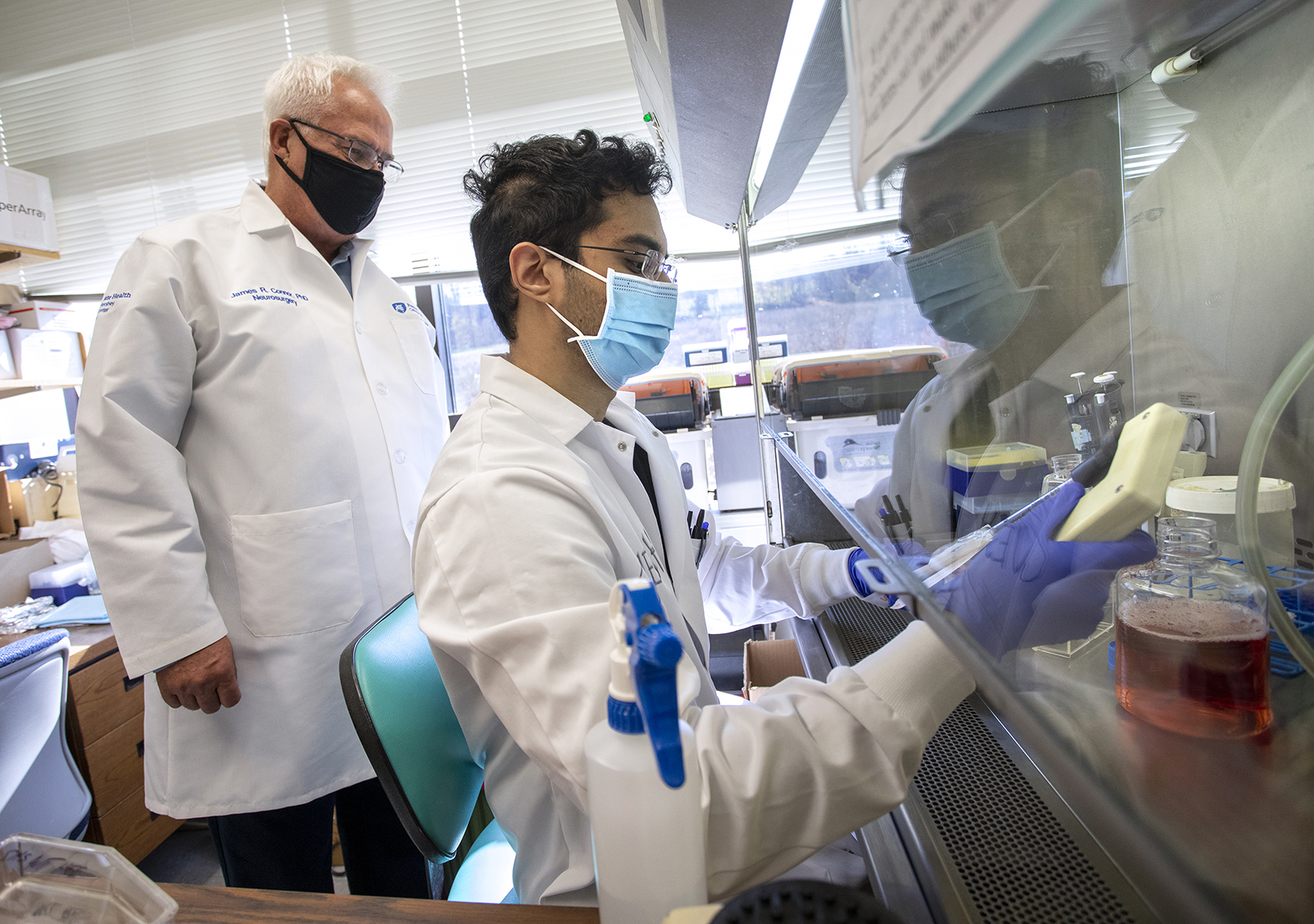 Two men in doctors' coats work in a research lab