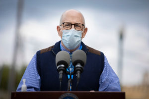 A doctor wearing a face mask speaks at a podium