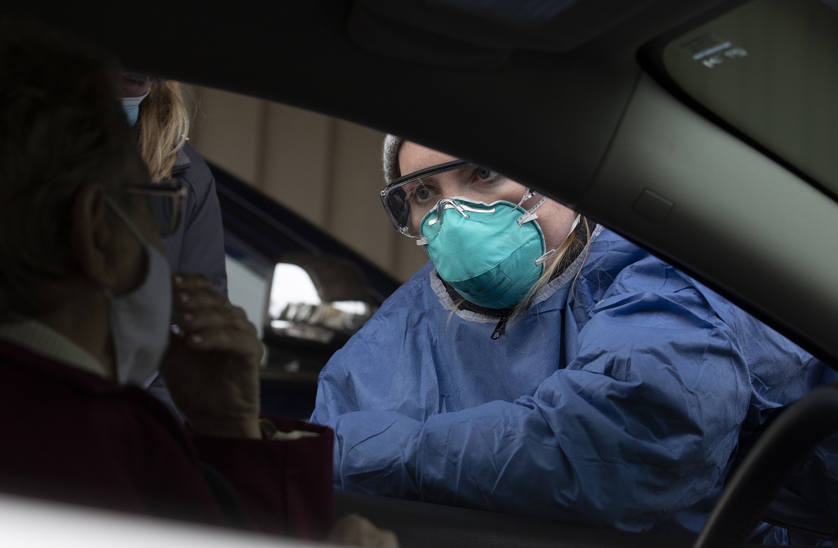 A nurse wearing a face mask gives instructions at a drive-thru COVID-19 testing site