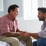 An adult son has a conversation about end-of-life care with his aging father.